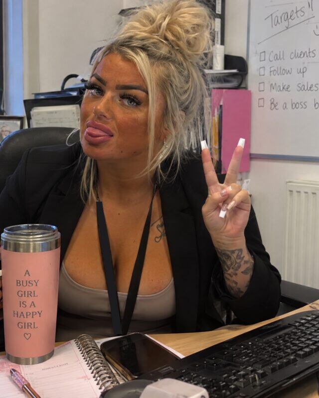 Kadey at her desk, giving a peace sign